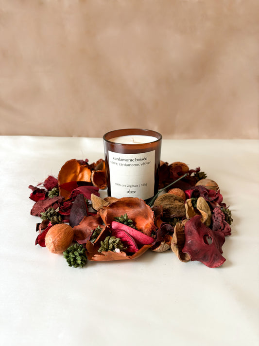 Bougie parfumée au cèdre et à la cardamome posée sur une table en bois, ambiance décoration d'intérieur naturelle et relaxante.